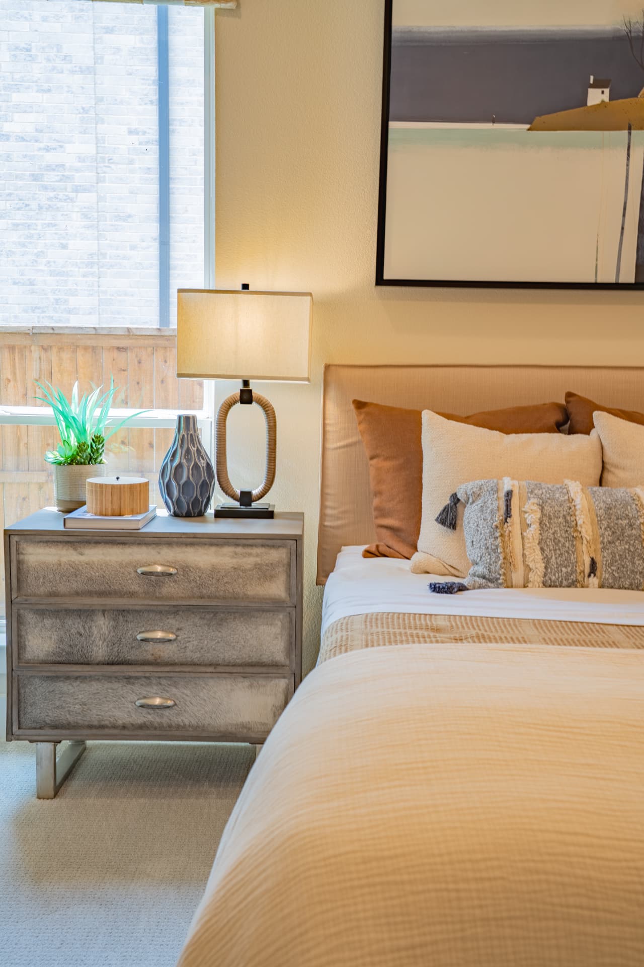 Nightstand vignette beside a made bed in warm light
