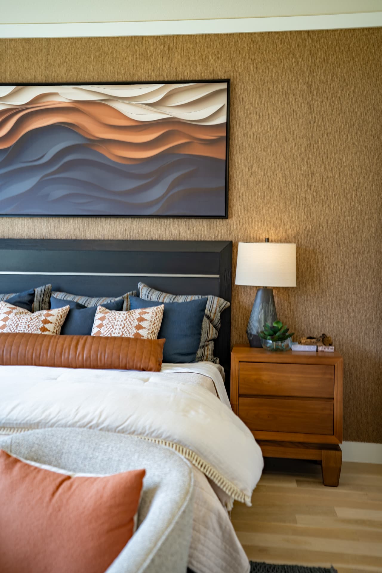 Primary suite with textured wall covering and layered bedding